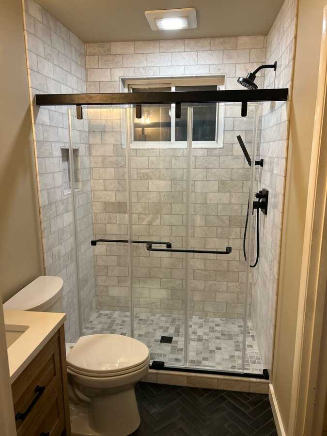 Finished bathroom remodel with tile shower, black shower hardware, and glass doors