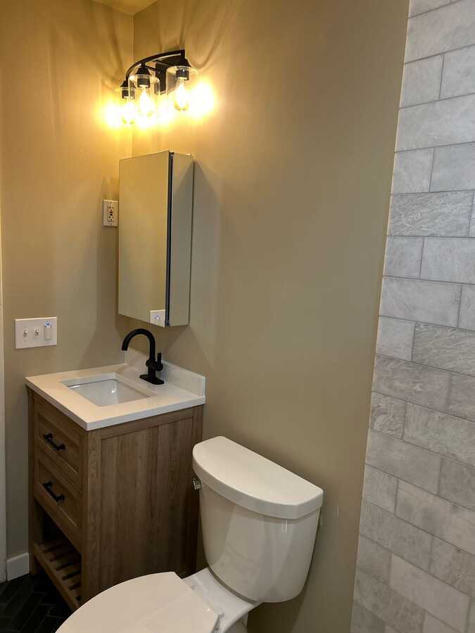 Bathroom vanity, mirror, light fixture, and tile shower wall